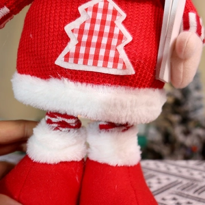 Close-up of red knitted Christmas doll sweater with plaid tree patch and faux fur trim
