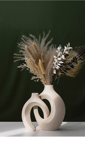 Detailed close-up of beige ceramic interlocking rings vase with speckled texture finish