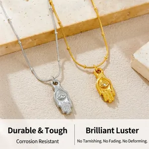 Detail of gold and silver Hamsa Hand pendants with evil eye motif on a stone background