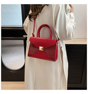 Detail of red tote bag featuring crocodile pattern stitching and a gold square buckle