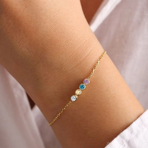 Dainty gold plated stainless steel bracelet featuring four colorful zircon gemstones on a wrist