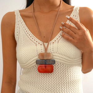 Close-up of geometric acrylic pendant with beige, blue-grey and red stacked rectangles