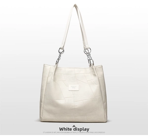 Close-up of cream large tote bag showing geometric patchwork texture and chain strap