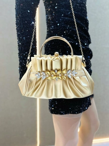 Detail of gold evening clutch with crystal flower pattern and metal ring handle