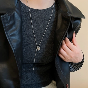 Detail of silver heart pendant on a Y-chain necklace worn with a stylish leather jacket