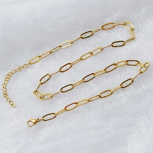 Golden paperclip chain necklace with lobster clasp on white fur background for women