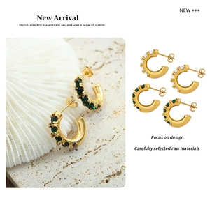 Détail de boucles d'oreilles en forme de C dorées 18 carats avec zircons verts