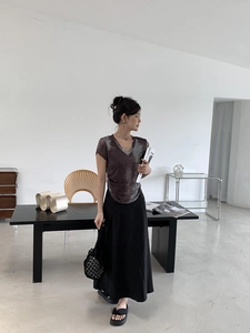 Detail of V-neck tie-dye short sleeve tee paired with a black midi skirt in a minimalist room
