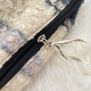 Gedetailleerd beeld van de zwarte rits op een cosmetische tas van krullend fleece