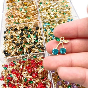 Teal cherry pendant with green leaves and colorful zircon stones in hand display