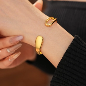 Detailed view of gold plated teardrop open bracelet on wrist with elegant metallic shine