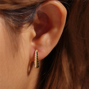Close-up of gold huggie earrings with double row black and white stones on model's ear