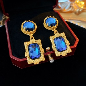 Détail de boucles d'oreilles vintage dorées avec gemmes bleues dans un écrin rouge