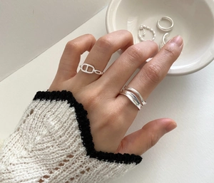 Detail of minimalist wave rings and sterling silver anchor link ring worn by a model