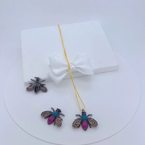 Detailed set of bee necklace and earrings with colorful crystals on a white pedestal