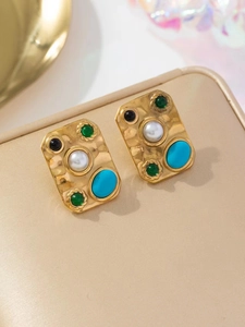 Détail de boucles d'oreilles vintage en or avec pierres colorées et perles sur coussin