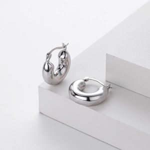 Macro shot of chunky 925 sterling silver hoop earrings with polished finish on white cubes
