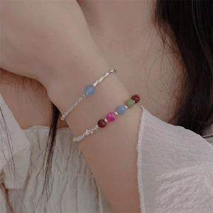 Close-up of elegant beaded bracelets with silver-toned chains and colorful gemstones