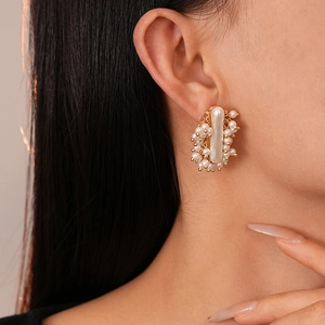 Close-up of French vintage style faux pearl cluster earrings with gold metal base on model