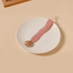 Détail de l'attache-tétine en mousseline rose avec clip rond en bois de hêtre naturel