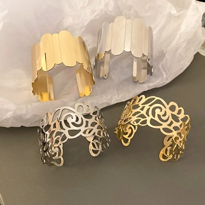 Detailed macro view of geometric wide metal bangles in polished gold and silver finishes