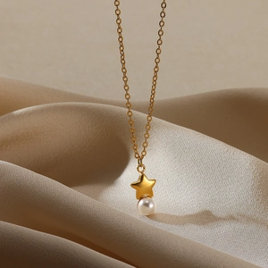 Close-up of matte 18K gold star and pearl pendant on a silk satin background