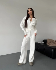Detail of white knit set featuring button-up cardigan and high-waist wide-leg pants