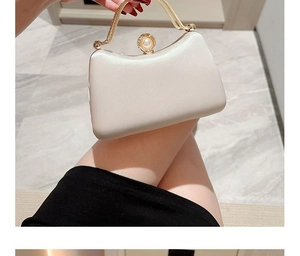 Detail of elegant ivory satin evening clutch bag with pearl clasp and gold metal handle
