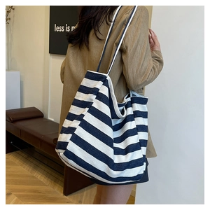 Lifestyle shot of large black and white striped canvas tote bag worn by a model