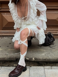 Detail of white ruffle long sleeve dress with V-neck and layered chiffon textures