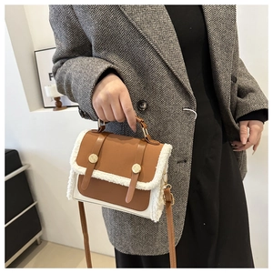 Detail view of brown and cream plush patchwork handbag with gold metal buckles on a model