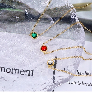 Macro shot of 18K gold-plated necklace with colorful round zircon pendants on glass