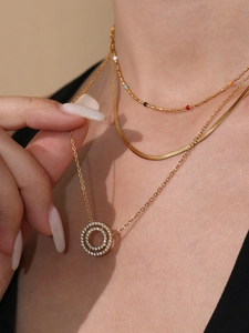 Close-up of layered gold necklace set with sparkling cubic zirconia pendant on model