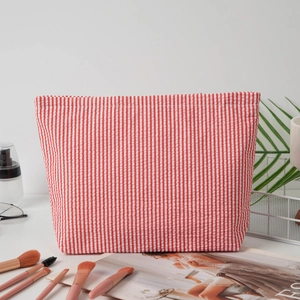 Detail of red and white seersucker travel toiletry bag with striped texture and zipper