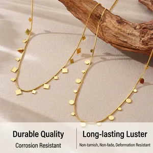 Detail of gold-plated snake chains with geometric square and round charms on wood
