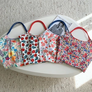 Close-up of four floral canvas tote bags with colorful flower patterns and rope handles