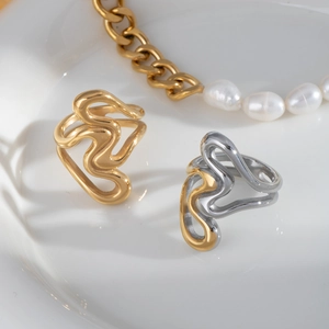 Détail de bagues dorées abstraites et collier de perles sur fond blanc