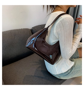Detail of glossy chocolate brown patent leather hobo bag with embossed side logo