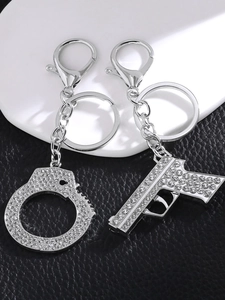 Macro view of silver rhinestone pistol and handcuff keychains on premium leather base