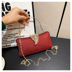 Detailed shot of red glitter evening clutch bag with golden leaf clasp and ring handle