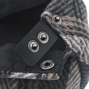 Close-up of grey tweed fabric and leather strap with metal button on a men's flat cap