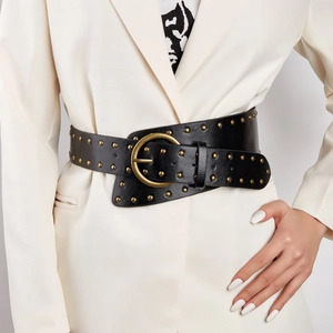 Punk style wide black leather belt with gold studs and round buckle on a white blazer