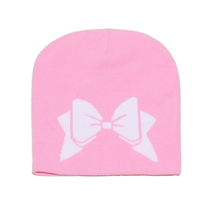 Détail du bonnet en tricot rose montrant le motif de nœud blanc et la texture douce