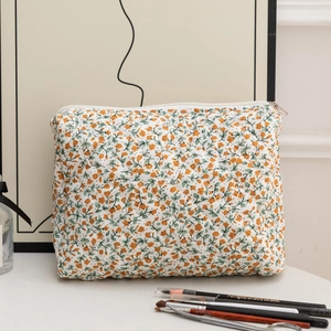 Detailed macro view of floral quilted makeup bag with zipper closure on desk
