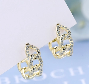 Macro shot of gold-plated Cuban chain hoop earrings with pavé set cubic zirconia stones