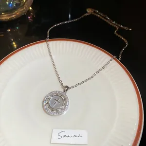 Détail macro du collier croix en argent plaqué or 18 carats avec zircons et nacre