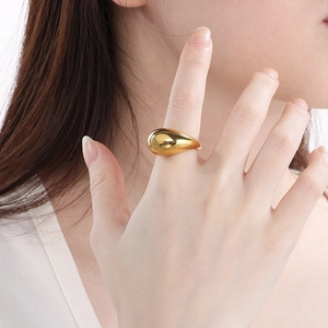 Close-up of a gold waterdrop ring on a model hand with a polished minimalist aesthetic
