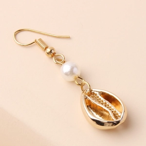 Close-up of golden shell dangle earrings with white pearls on a minimalist background