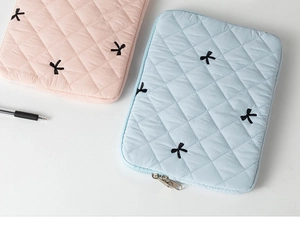 Detailed close-up of quilted tablet sleeve with cute embroidered black bows