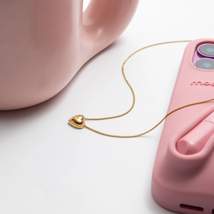 Detail of 18K gold stainless steel heart necklace with crystal on a pink phone case